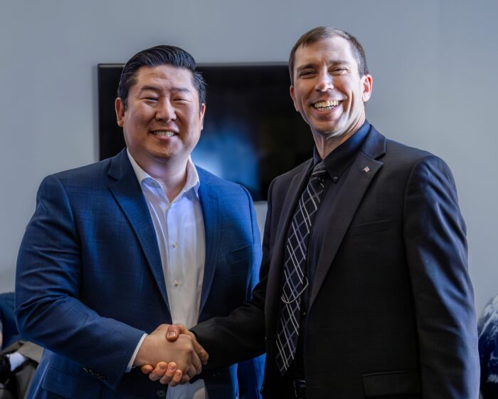 Millenium Space Systems' CEO, Jason Kim shaking hands with Derek Tournear, from the SDA.
